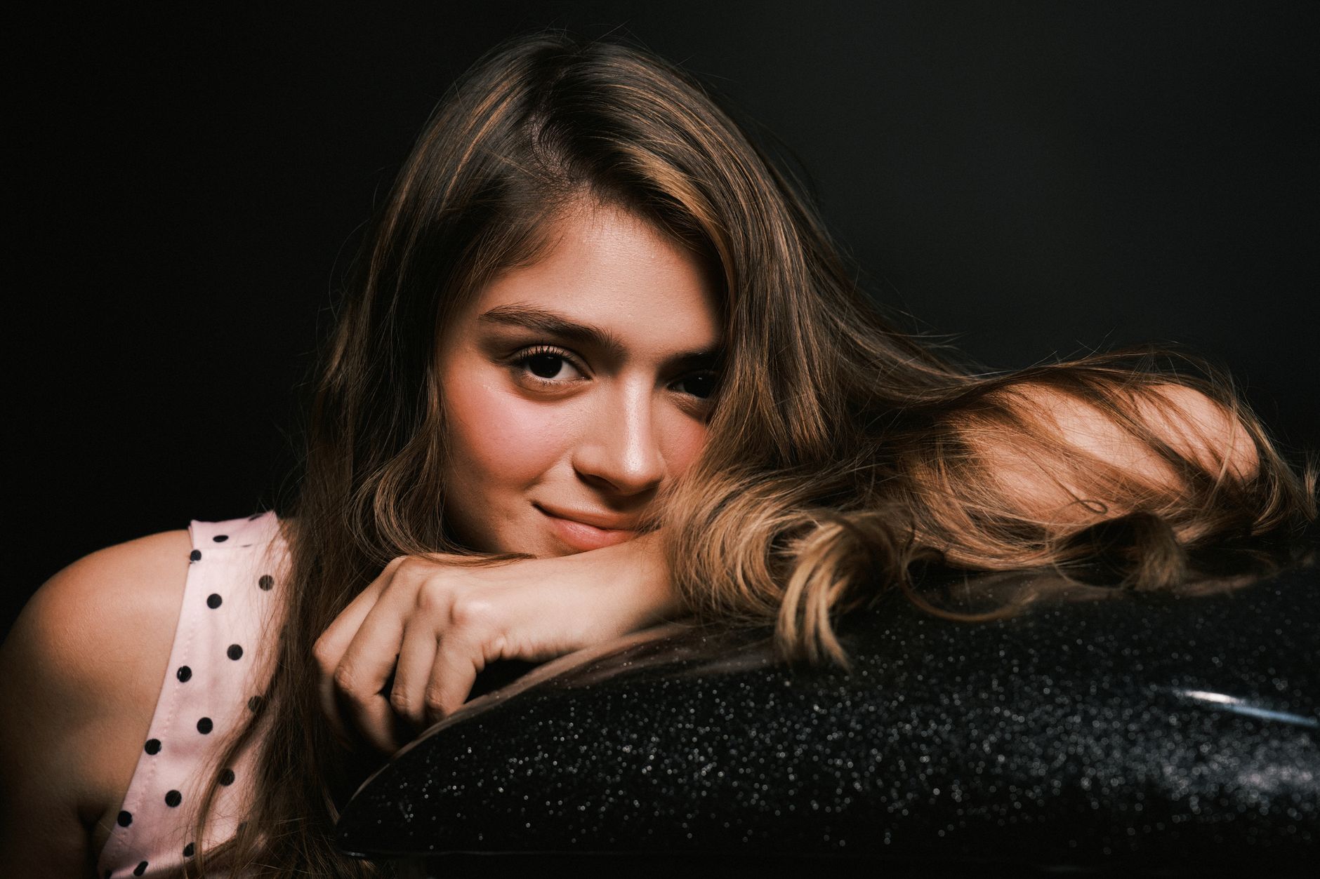 Captivating portrait of a young woman with long hair and a gentle smile, set against a dark background.