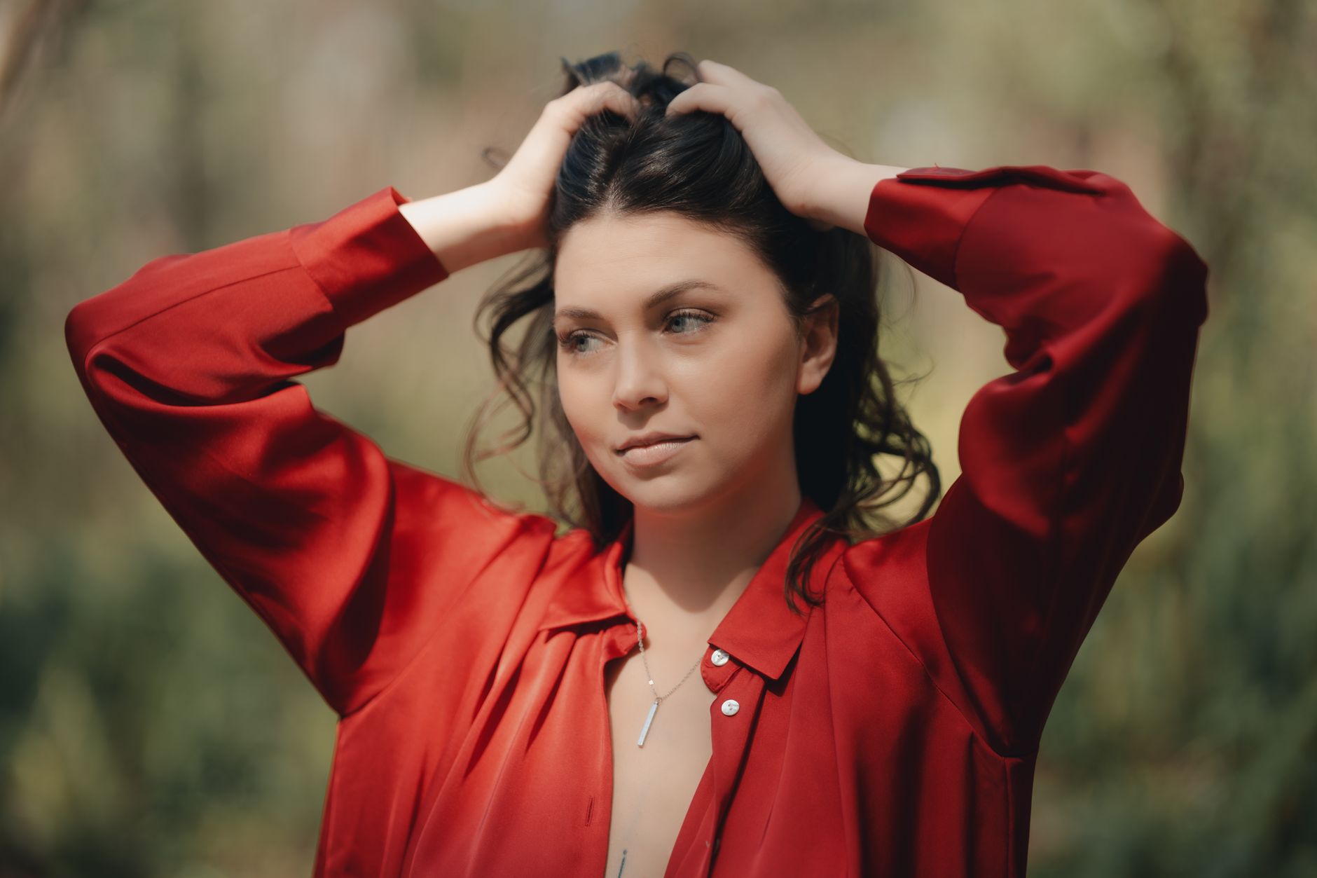 Portrait of a young woman with a red shirt posing outdoors in natural light.