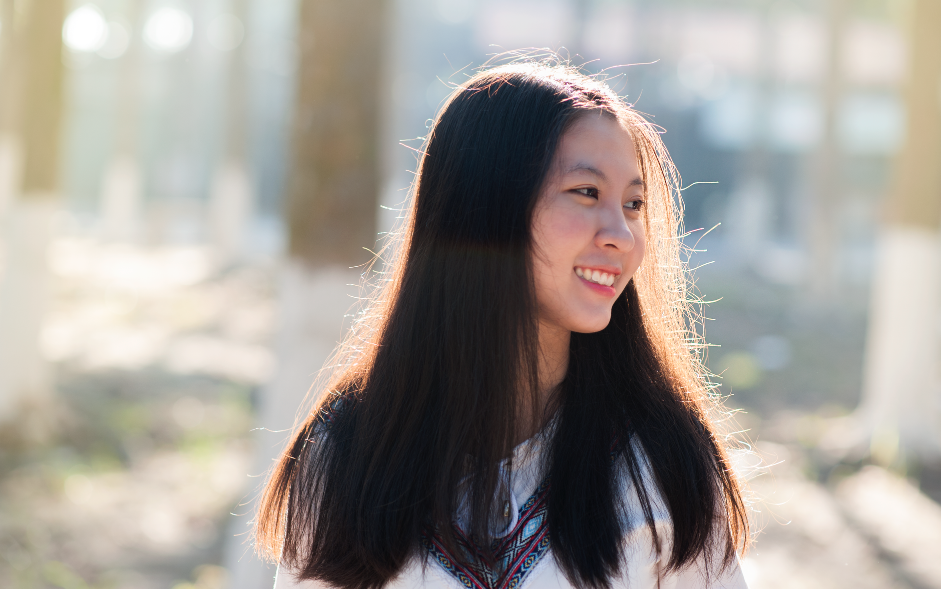 Portrait of a happy young woman smiling in natural sunlight outdoors, capturing a moment of joy and tranquility.