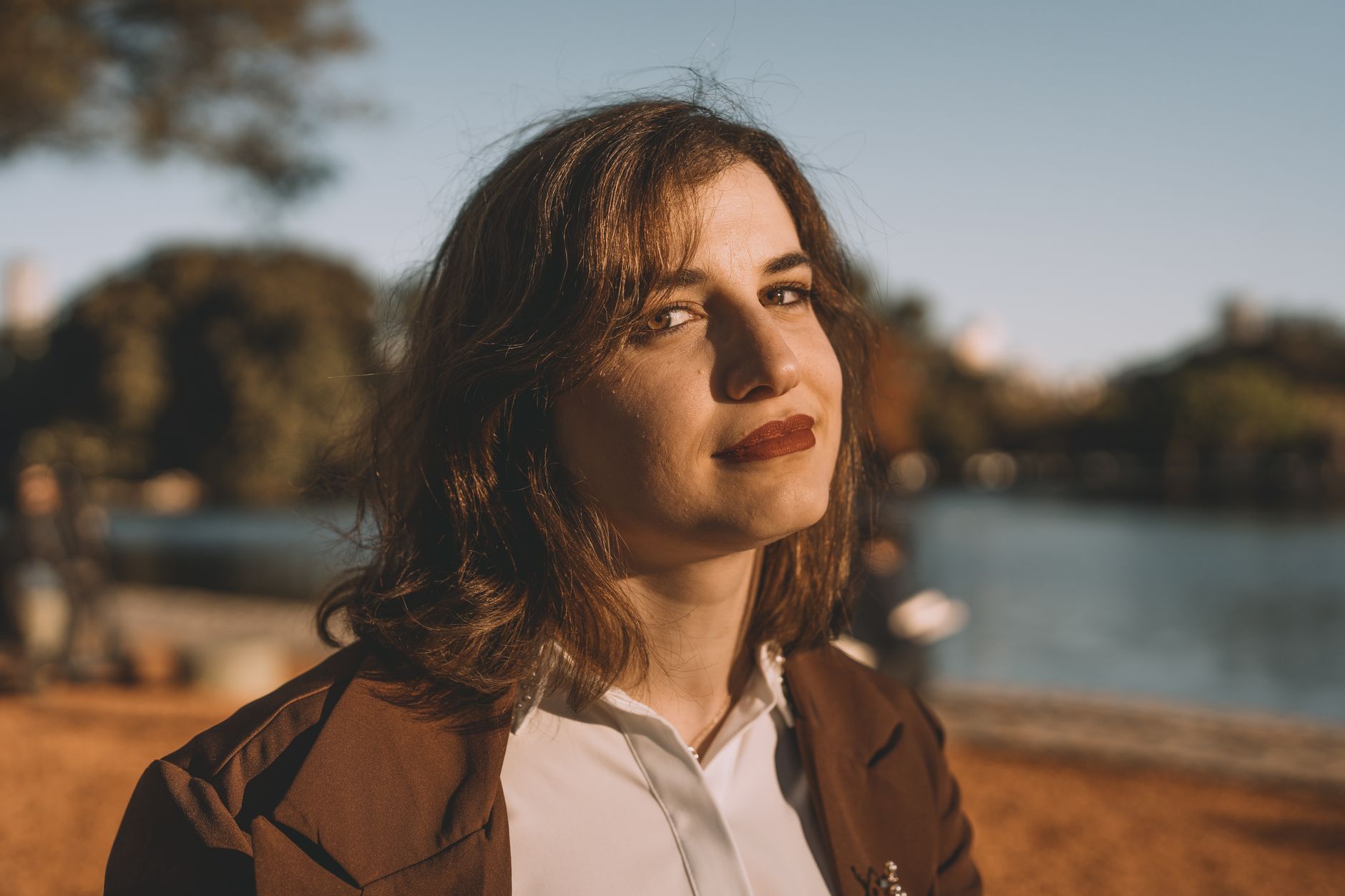 Woman smiling by a lakeside in Buenos Aires during a sunny day.