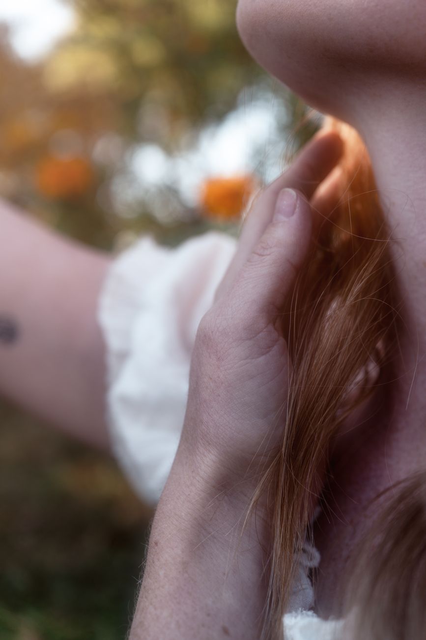 Soft focus image of a hand touching a neck in a natural setting with warm tones.