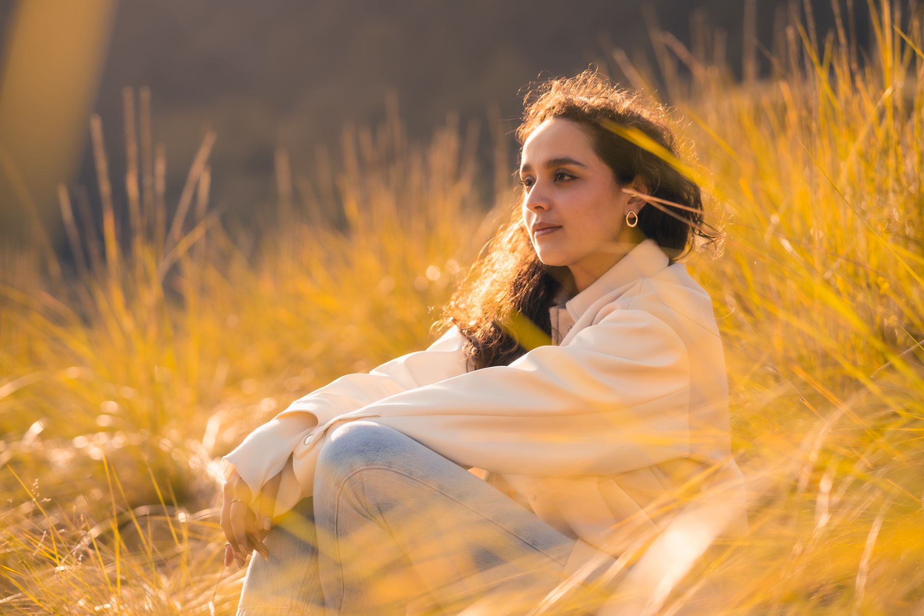 A woman enjoys the serene beauty of a sunlit field, embracing tranquility during golden hour.