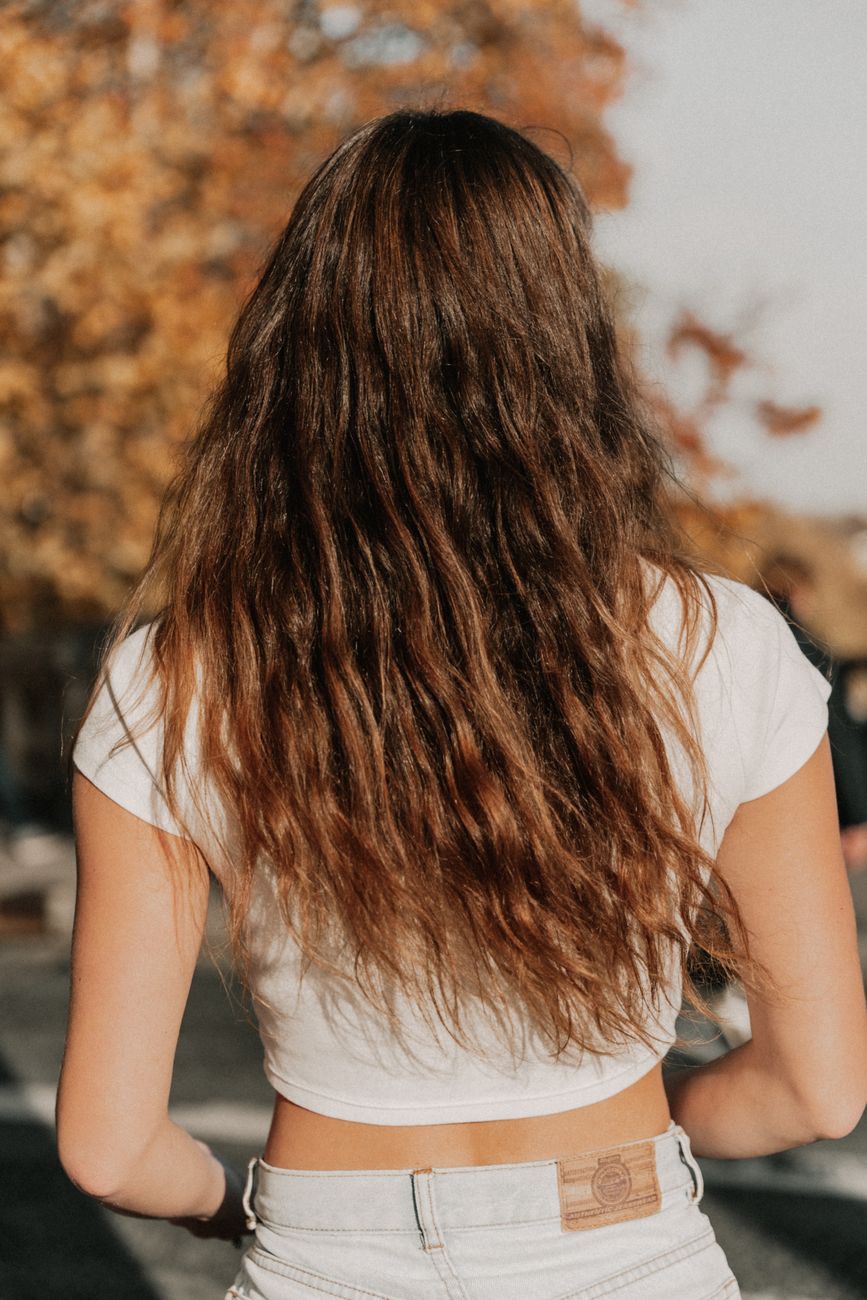 Back view of a woman with long hair wearing a white top in autumn.